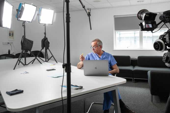 Professor Darzi sits at a table under bright lights, recording an instructional video
