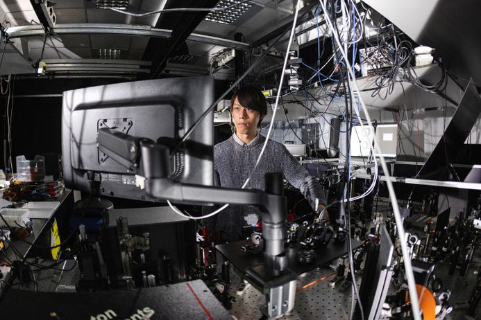 A PhD works at a computer in the ultrafast plasmonics lab, surrounded by wiring