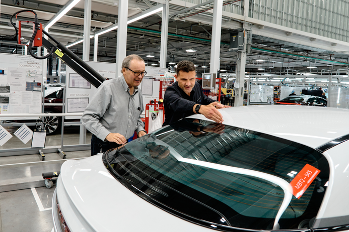 Two people revise a new car in the factory