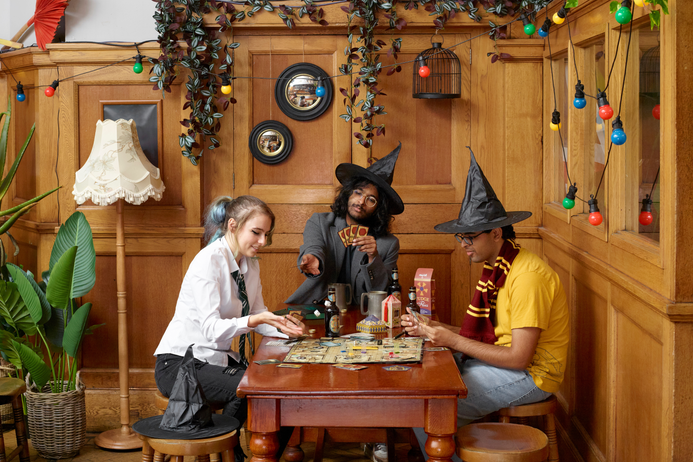 3 members of the harry Potter society play a game on a table