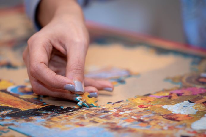 Hand placing a piece of a jigsaw puzzle