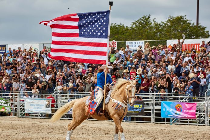 Woman on horse with America flag at a rodeo