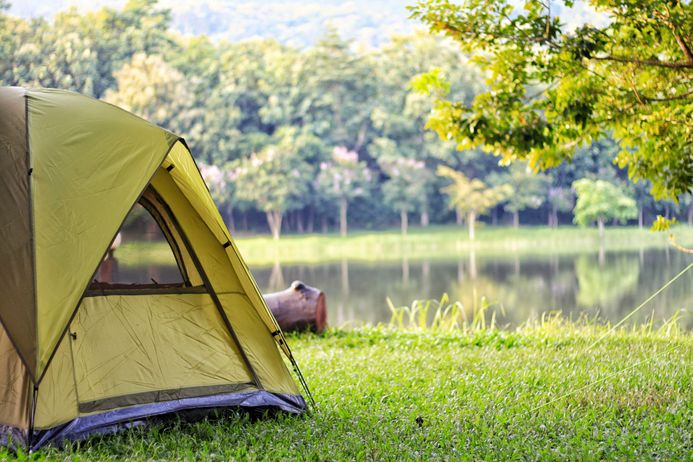 yellow camping tent in grass along side a lake