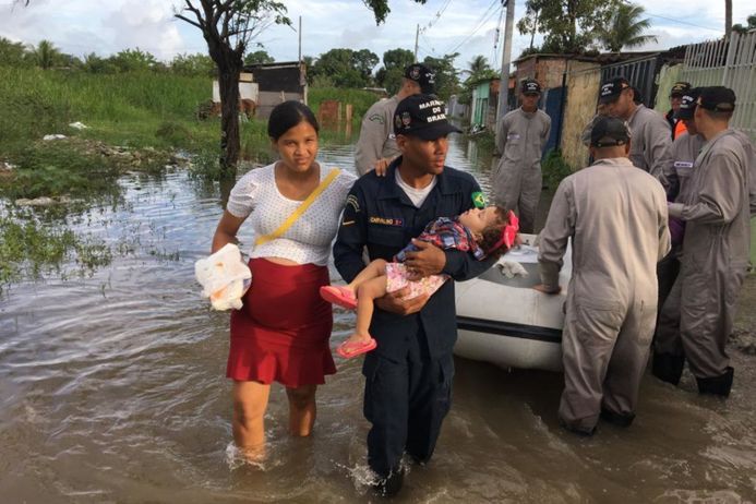 woman and man carry toddler through flooded streets