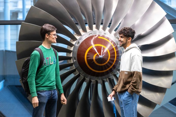 Students standing by a jet engine fan