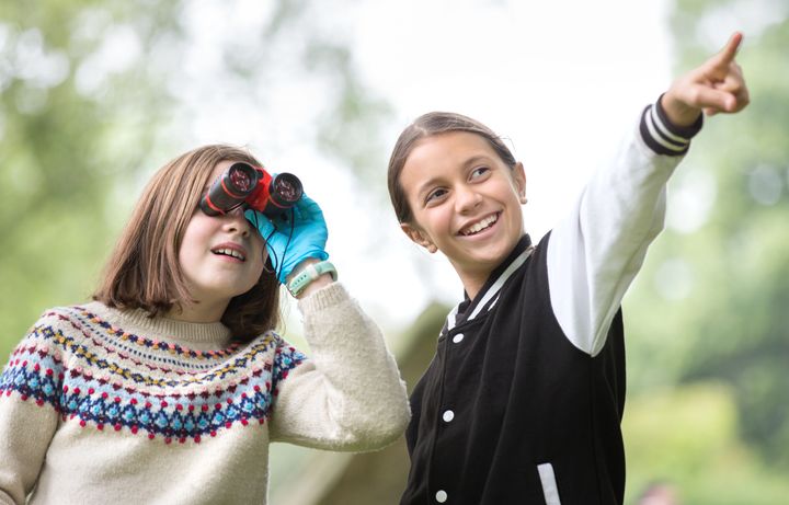 child pointing and friend looking through binoculars