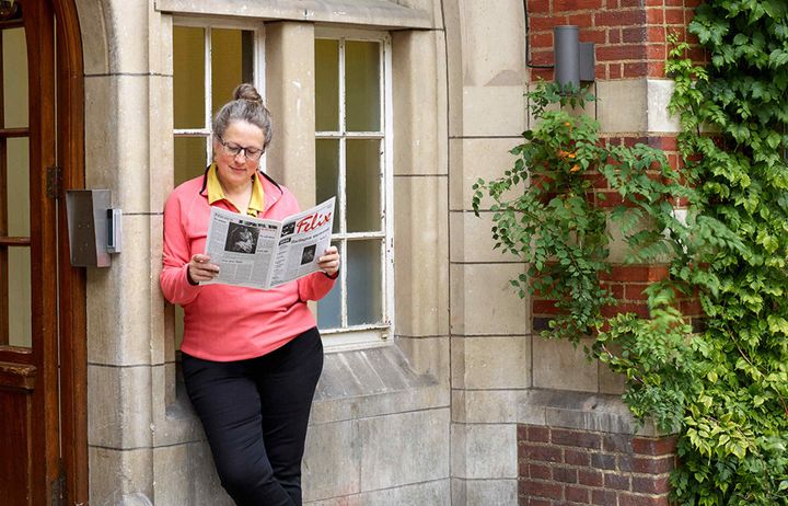Former editor of Felix Judith Hackney reading an archive copy of the paper outside the main building at Beit Quad