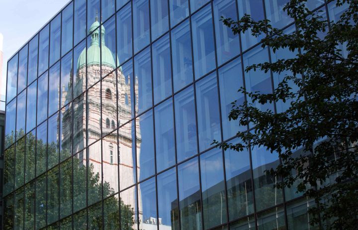 Queen's Tower reflected in windows of glass building