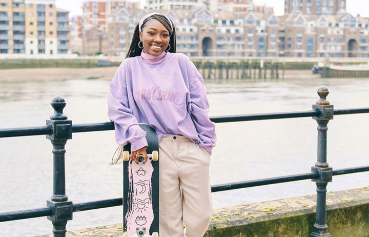 Jessica Powell with her skateboard standing by the river
