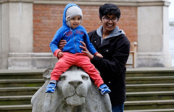 A parent holding a child on a stone lion