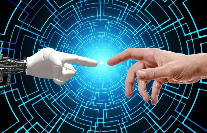 Artist's impression of a robot hand and a human hand reaching out to touch each other over a tech background