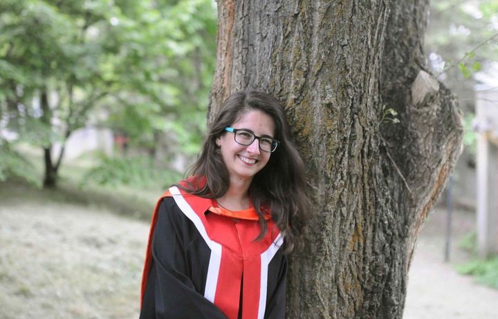 Deniz Goren in her graduation robes by a tree