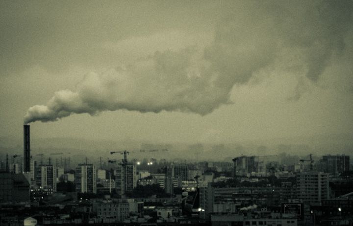 smoke stacks above a city with a thick plume of smoke