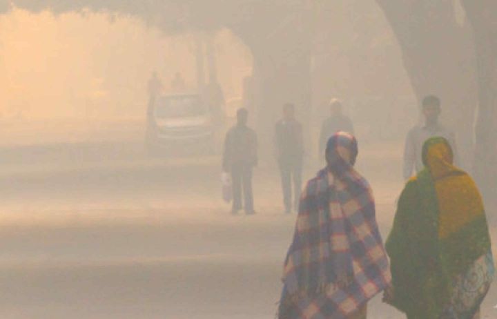 Two women walking along a road that is hazy with air pollution
