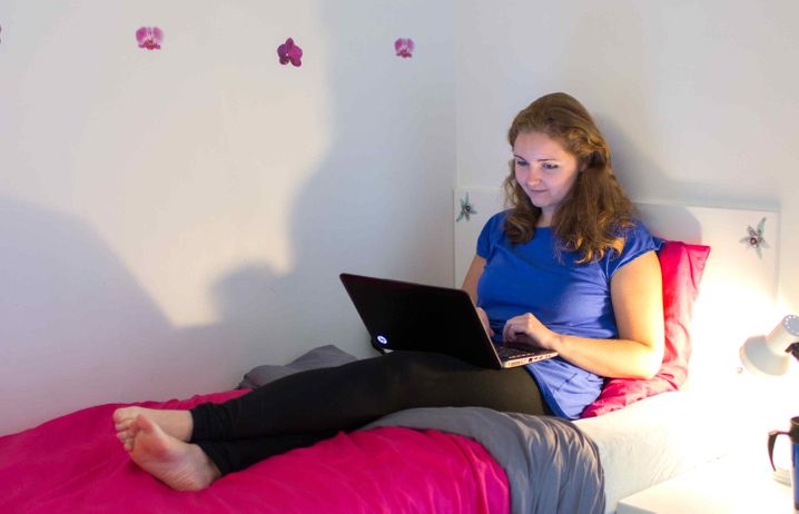 Student on laptop on bed in halls