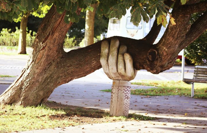 carving of hand holding up branch