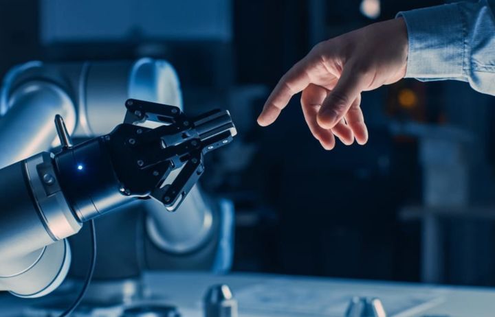 Human hand and robotic claw reaching to one another