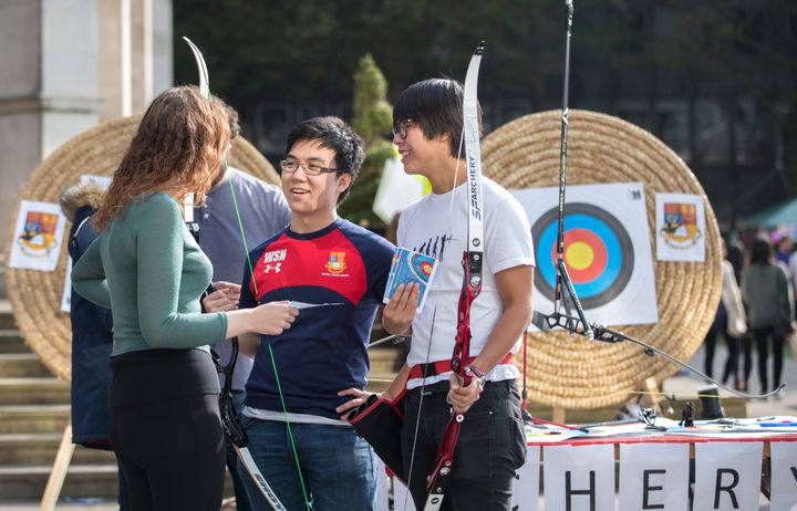 Students speaking to an archery club organiser.