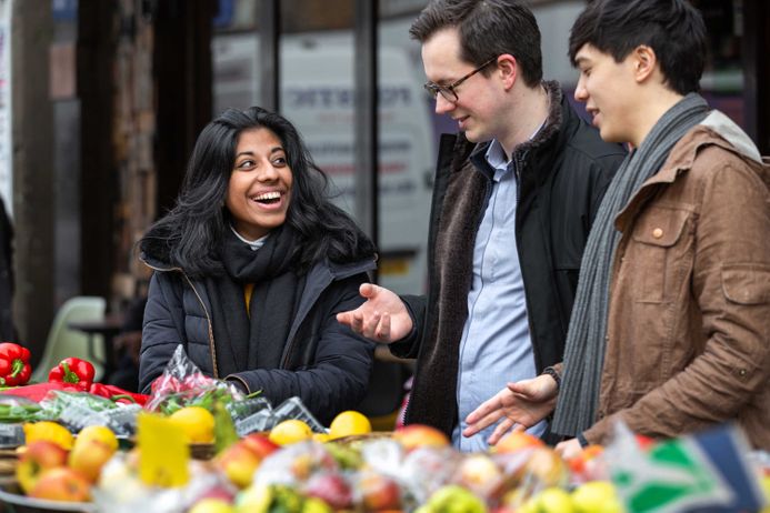 Three students standing by produce outside in Fulham Market