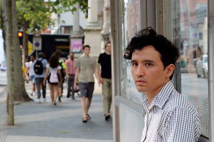 portrait of a male student in front of a busy street