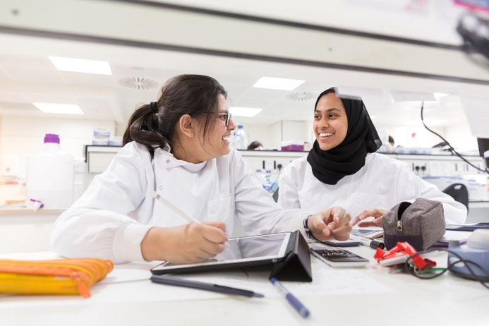 Two students in a lab coats engaged in a conversation