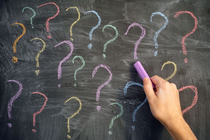 Chalk question marks in different colours on a blackboard