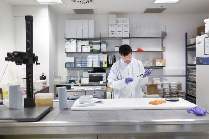 A researcher uses a pipette to take a sample from a piece of brain tissue