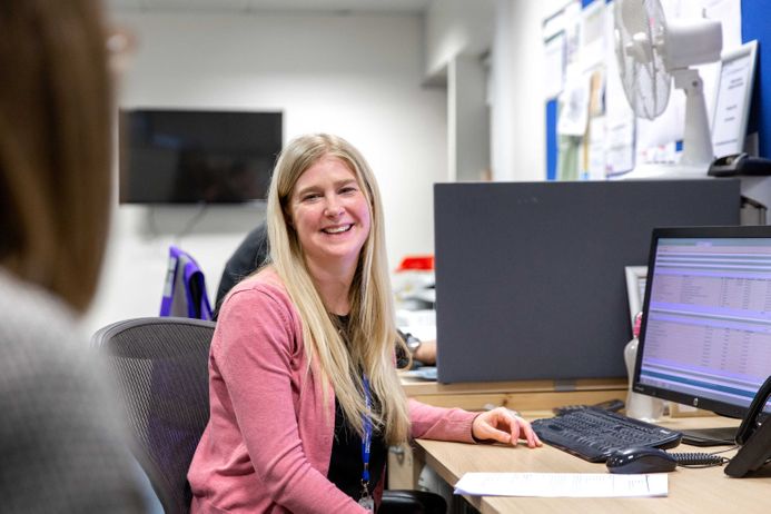 An administrator working at a computer and smiling