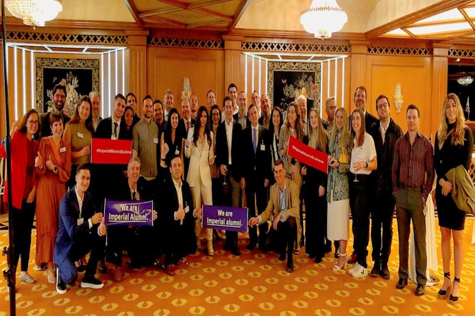 Large group of alumni at an event holding Imperial banners