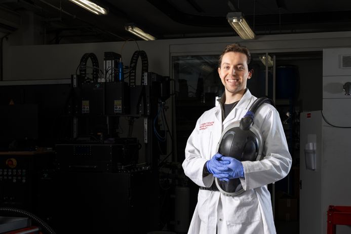 A researcher in a lab coat next to large equipment