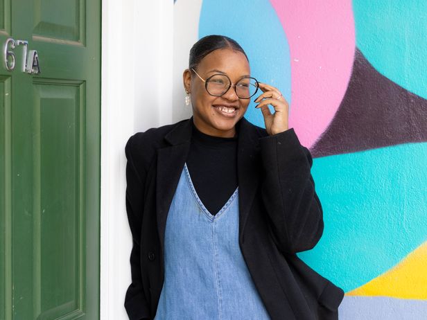 Female student in glasses standing against colourful wall