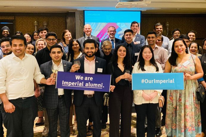 Group of alumni at an event holding Imperial banners