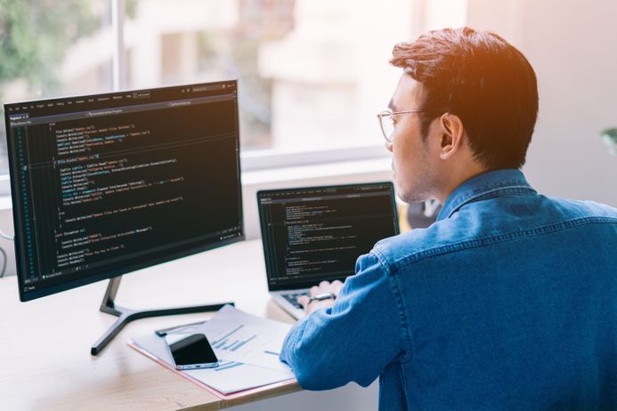 Man sitting at computer with code on it