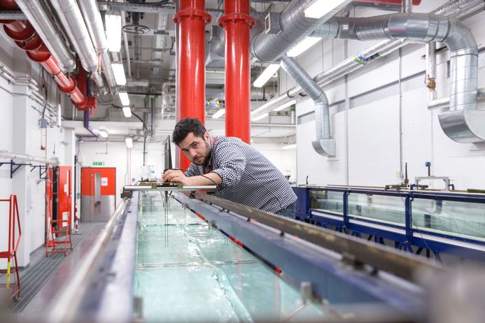 A researcher sets up a rig above a water tank in the fluid mechanics laboratories