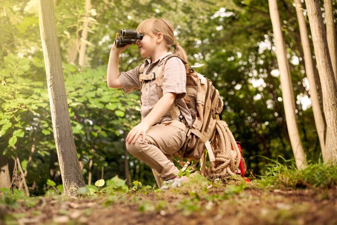 girl hiking with backpack on a forest road bright sunny day