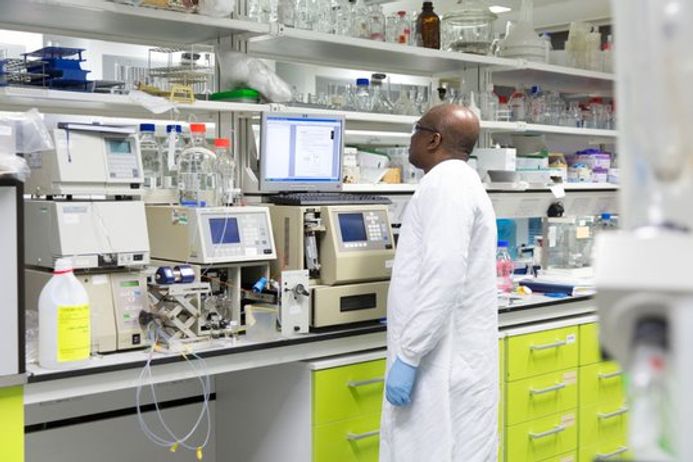 A researcher in a lab coat looks at a computer screen during an experiment