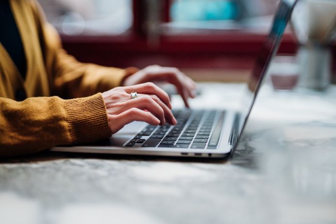 Cropped photo of person with hands typing on a laptop