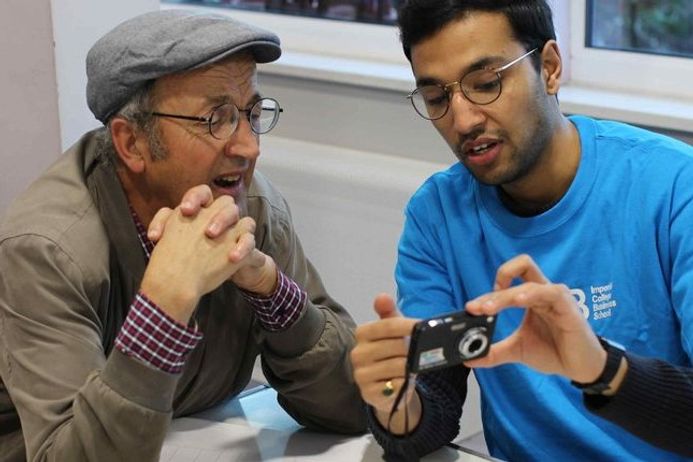 An Imperial College Business School student helps a man with his camera