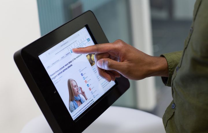 A hand touching a tablet device.