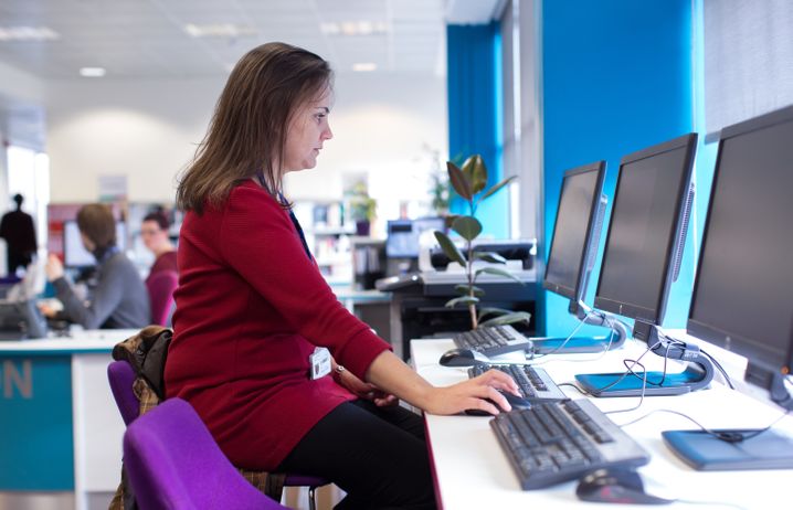 A member of staff sat at a computer.