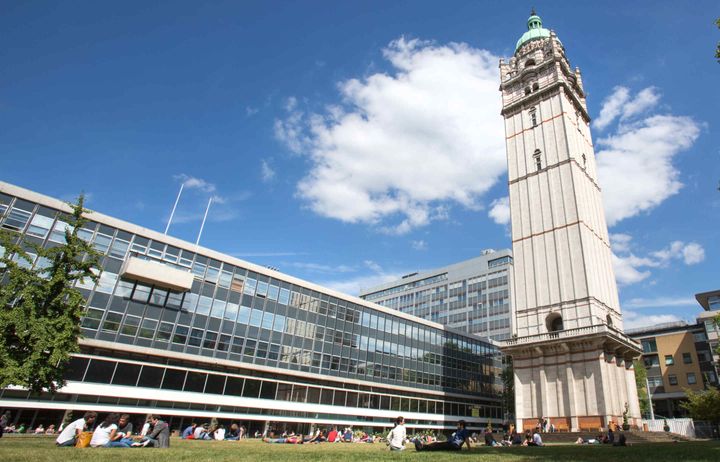 Photo of the Queen's Tower and lawn with students enjoying the spring sunshine