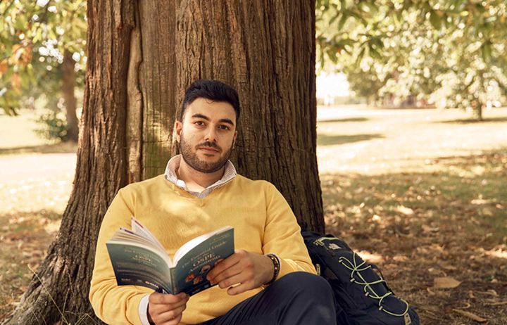 Student Arian Arjomandi Rad sat beneath a tree in Hyde Park and holding a book