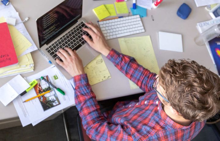 Workplace desk with man working on laptop