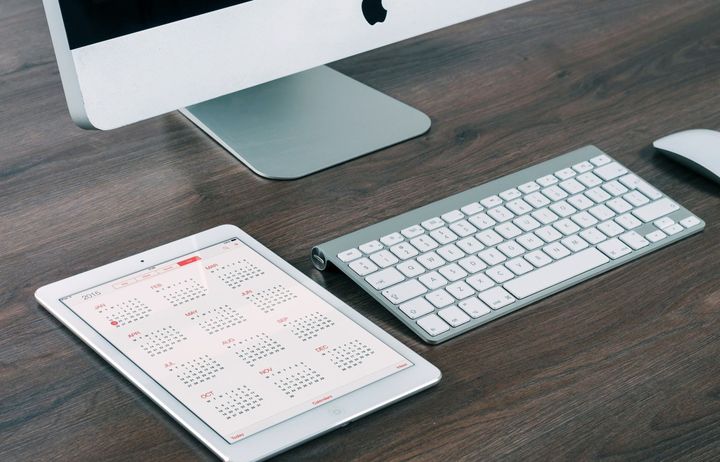 A calendar displayed on a tablet next to a Mac computer