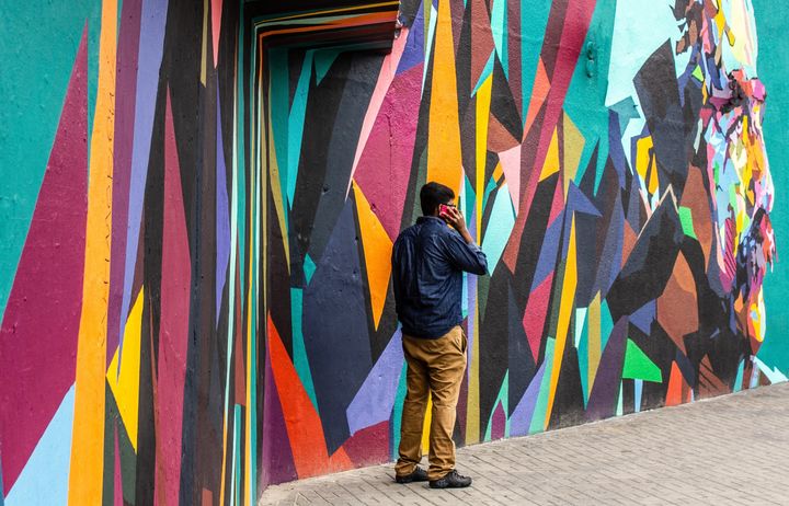 male on phone in front of wall art