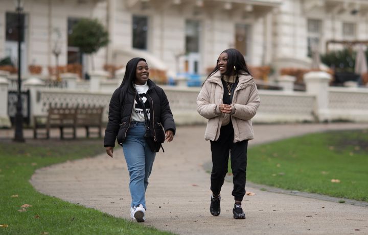 Two students walking in park near campus