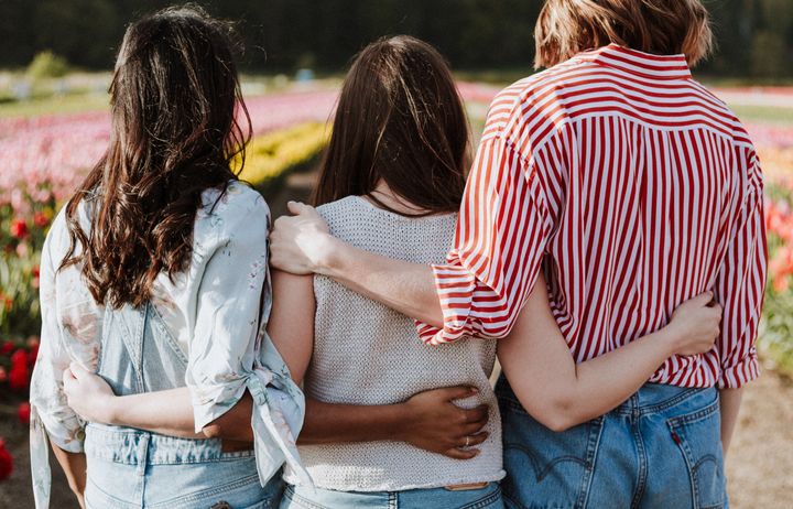 3 women with arms around each others shoulders