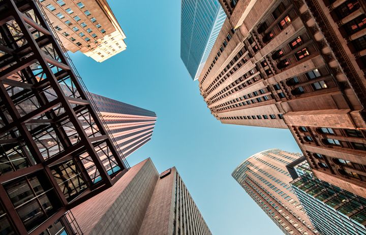 View looking up to blue sky through tall buildings