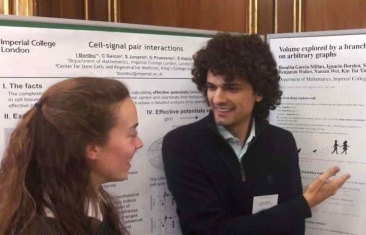 People talking at a workshop in front of posters of their research.