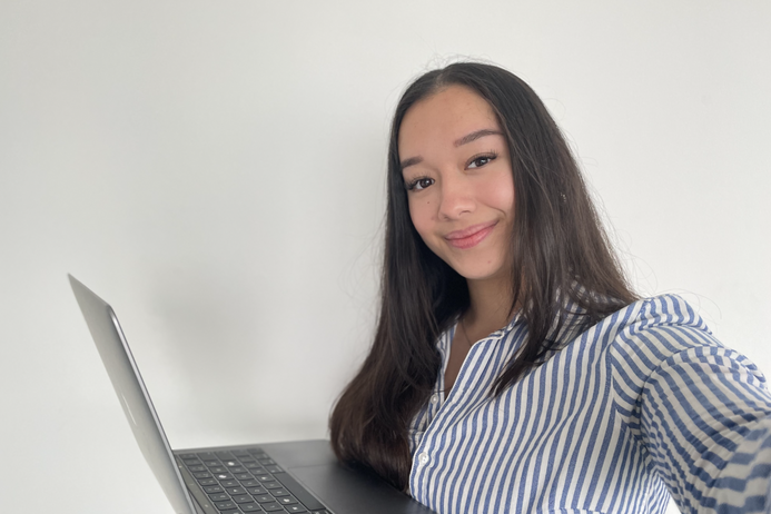 portrait of a young woman with long brown hair holding a laptop